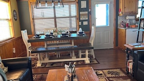 Una sala de estar acogedora con una mesa de centro de madera, un sofá y una zona de comedor con un banco.
