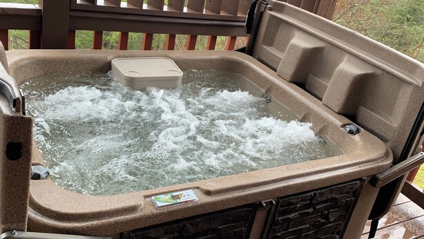 Un jacuzzi con terraza de madera y vistas al follaje circundante.