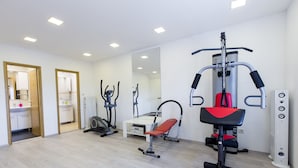 Une salle de sport équipée de machines de cardio, d’un banc de développé couché et d’un mur recouvert de miroirs.