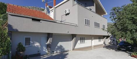 A two-story house with a red-tiled roof, a satellite dish, and a garage.