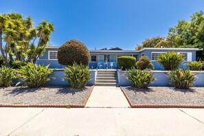 Uma casa moderna com vista clara para a entrada, um jardim bem cuidado e uma escadaria que leva à entrada.