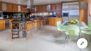A modern kitchen with wooden cabinets, stainless steel appliances, and a central island with bar stools.