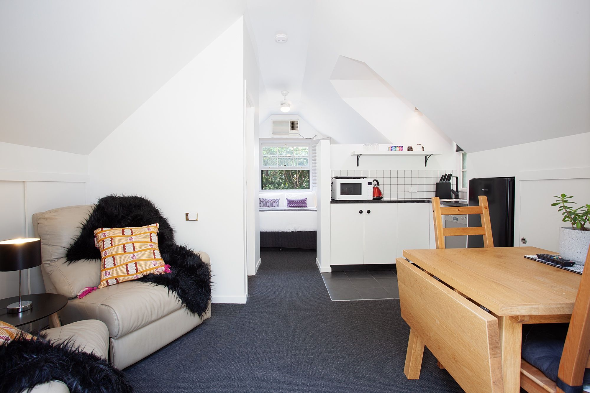 A compact living space with a kitchenette, a sofa, a dining table, and a ceiling fan.