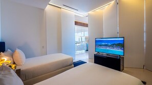 A modern hotel room with a bed, a TV, and a view of a beach.