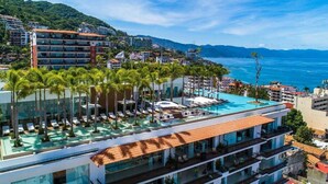 Ein Resort mit einem Pool auf dem Dach, Palmen und Blick aufs Meer.