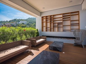 Un área de estar moderna al aire libre con terraza de madera, banco integrado y estantería de pared.