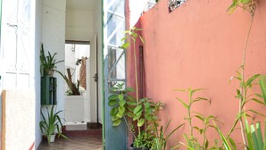 A narrow pathway leading to a door with potted plants on either side.