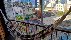A hammock on a balcony with a city view.