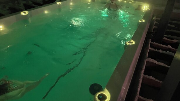 A hot tub with a person in it, surrounded by lights.