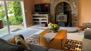 A living room with a stone fireplace, a flat-screen TV, and a sofa.