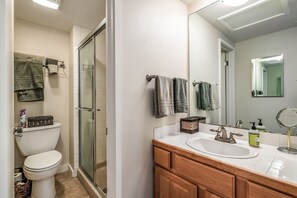 A bathroom with a toilet, shower, and sink.
