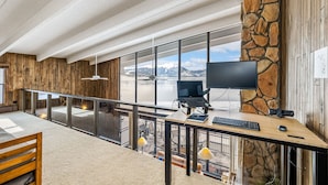 Un ufficio moderno con una scrivania grande, un computer e vista su un paesaggio innevato attraverso ampie finestre.