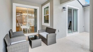 A patio area with wicker furniture, a table, and a glass door leading to an indoor space.
