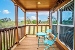 Una terraza de madera con una mesa y sillas, con vista a un área verde.