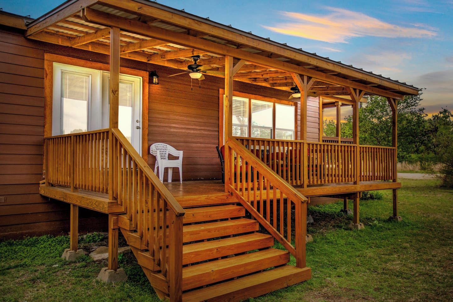 Une cabane en bois avec une véranda, un escalier et une seule chaise.