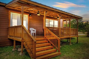Eine Holzhütte mit Veranda, Treppe und einem einzelnen Stuhl.