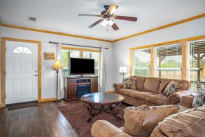 A living room with a television, a ceiling fan, a fireplace, and a couch.