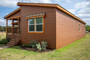 A single-story wooden house with a porch, a small deck, and a front door. - River Bend Hideaway | 3BR Retreat w/ River Access (Medina)
