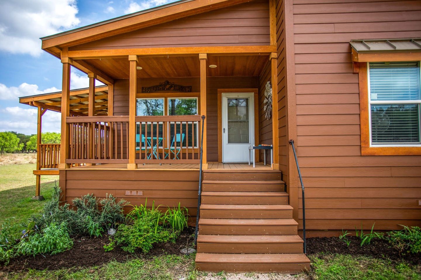 A wooden house with a porch, a door, and a window.