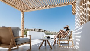 A terrace with wooden furniture, a round table, and a view of the landscape.