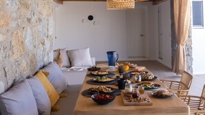 A dining area with a stone wall, a wooden table set with various dishes, and a cozy seating arrangement.