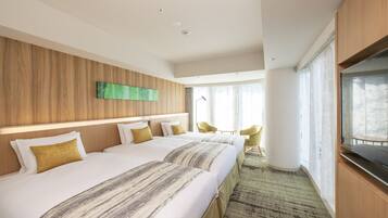 A hotel room with two beds, a TV, a large window, and a view of the outdoors.