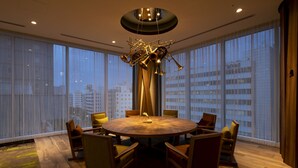 A modern dining area with a round table, chairs, and a unique brass sculpture. - Hotel Grand Bach Sendai (Sendai)