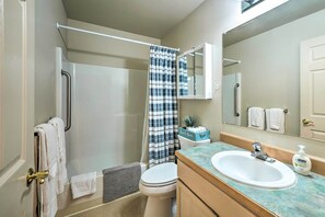 A bathroom with a shower, toilet, sink, and a mirror. - Anacortes Condo - Walk to Town, Marina, + Bay! (Anacortes)