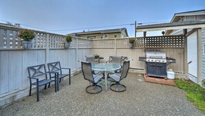 A backyard with a barbecue grill, a round glass table with four chairs, and a wooden fence. - Anacortes Condo ~ 1 Mi to Marina & Fidalgo Bay! (Anacortes)