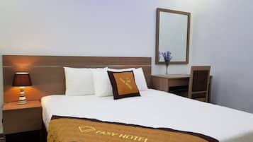A neatly made bed with a brown and white bedspread, a nightstand with a lamp, and a small table with a vase of flowers.