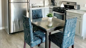 Una cocina moderna con armarios blancos, electrodomésticos de acero inoxidable y una mesa de comedor con sillas.