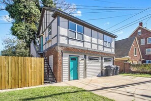 A two-story house with a garage, a wooden fence, and a green door.