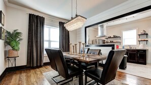 A dining area with a wooden table, black chairs, a chandelier, and a potted plant.