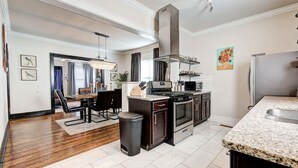 A modern kitchen with granite countertops, stainless steel appliances, and a dining area with a chandelier.