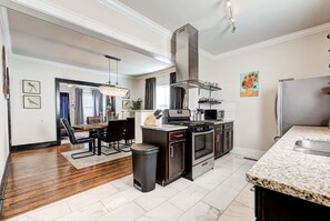 A modern kitchen with granite countertops, stainless steel appliances, and a dining area with a chandelier. - Howes Capitol–3 in 1-near OU Med, Bricktown, Arena (Oklahoma City)