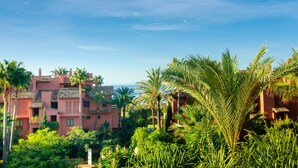 A residential area with multiple buildings, including a pink building with a tiled roof and balconies. - Beachfront Luxury | Renovated 2-Bed Oasis with Pool Access at Alicate Playa (Marbella)