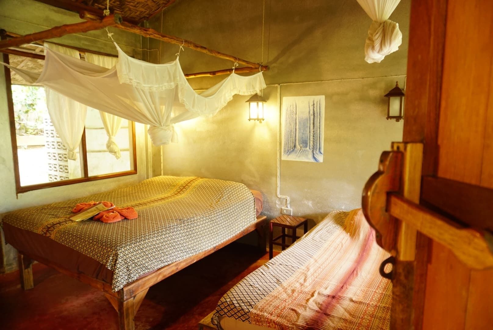 Una habitación con cama, una mesita pequeña, una silla colgante y una ventana con cortinas.