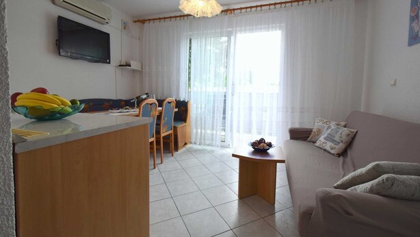 A living room with a sofa, a coffee table, and a dining area with chairs and a table. - Apartment Sunny on the first floor (Njivice)
