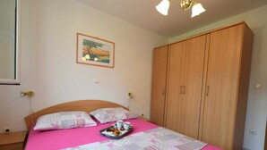 A bedroom with a bed, a wardrobe, a painting, and a tray with a cat and cups. - Apartment Sunny on the first floor (Njivice)