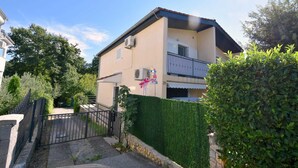 A two-story building with a balcony, a gated entrance, and a well-maintained hedge. - Apartment Sunny on the first floor (Njivice)