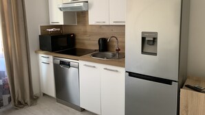 A modern kitchen with a dishwasher, microwave, sink, and refrigerator. - Magnificent Studio in the historic heart of Fréjus (Fréjus)