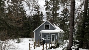 A snow-covered path leading to a house with a wooden fence.