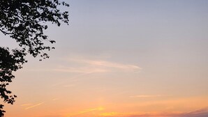 A sunset over a calm sea with a beach in the foreground.