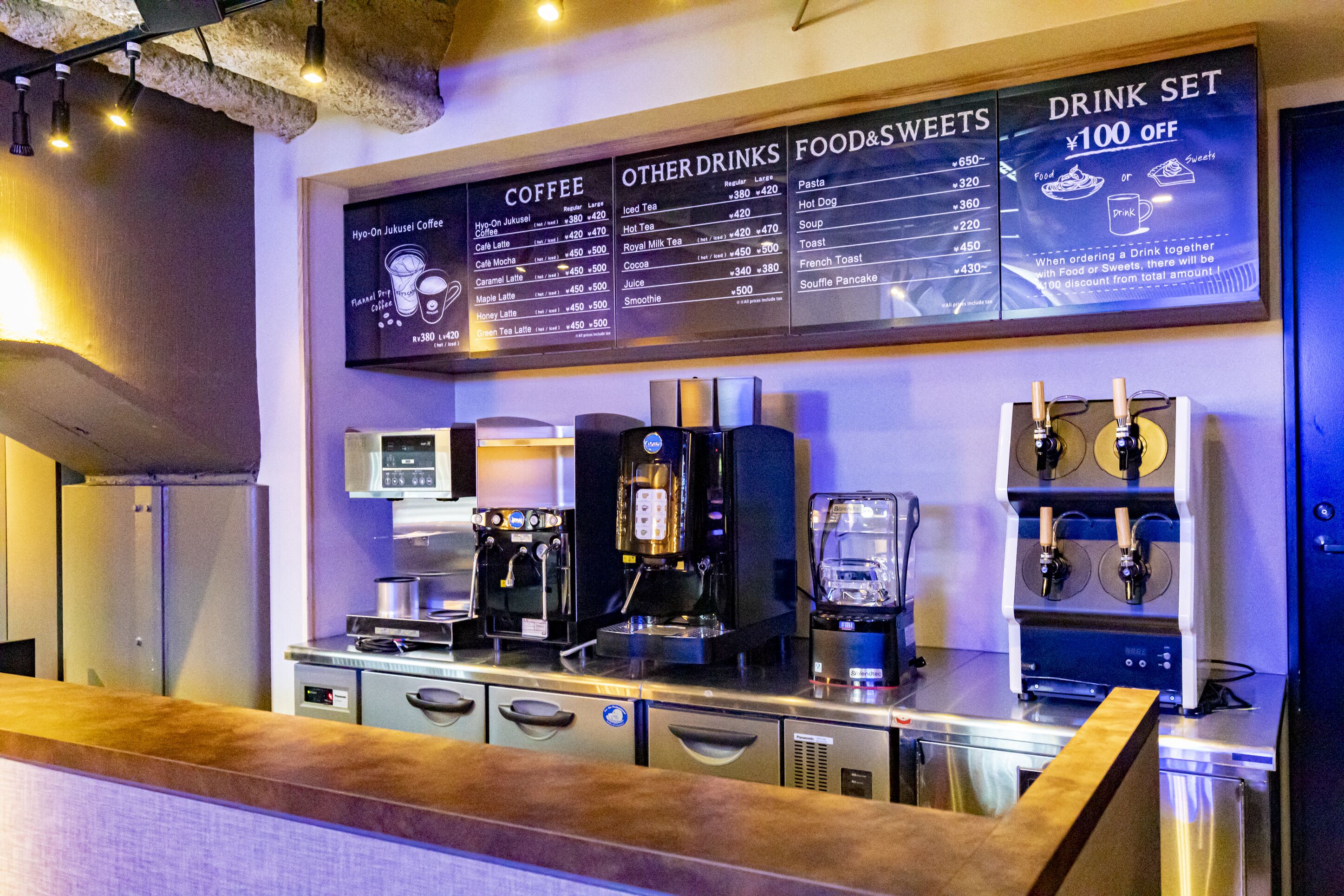 Un café con una pizarra que muestra café, otras bebidas y comida con dulces.