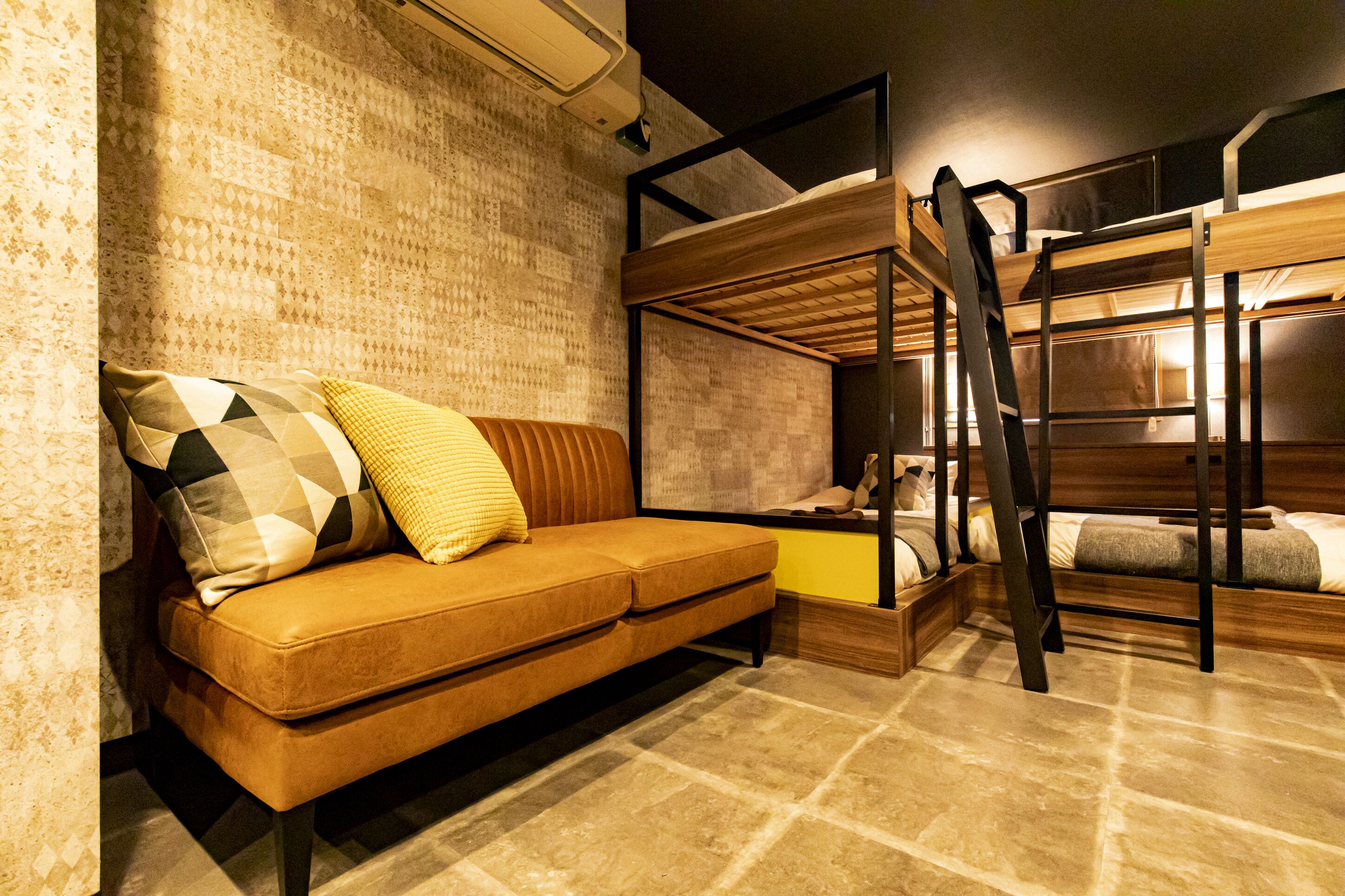 Un lit superposé avec une échelle, un canapé avec des coussins à motifs et un mur décoré de motifs.