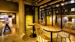 A modern interior with a café area, wooden furniture, and large windows.