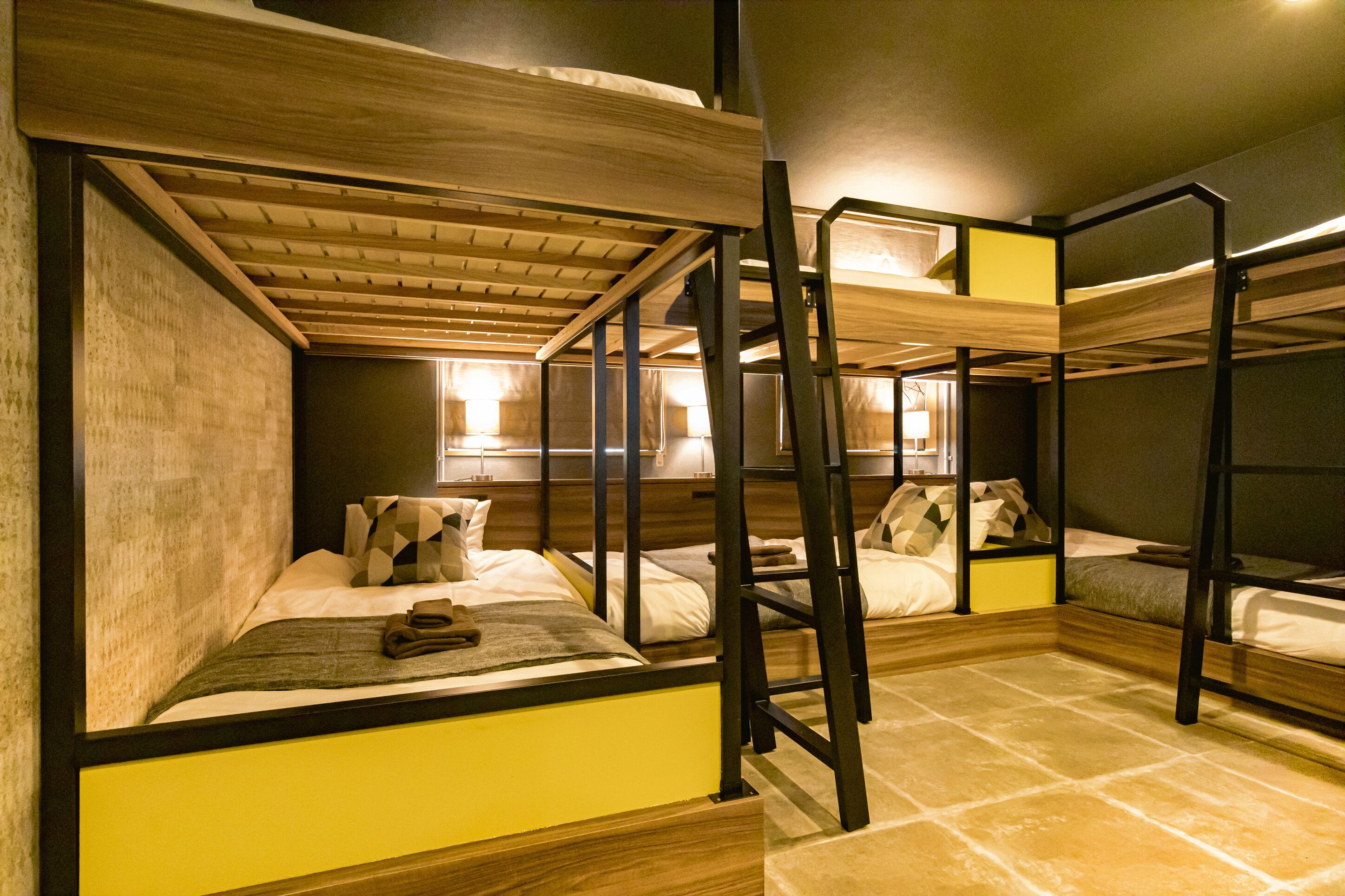 Una habitación con literas, techo de madera y suelo de baldosas.