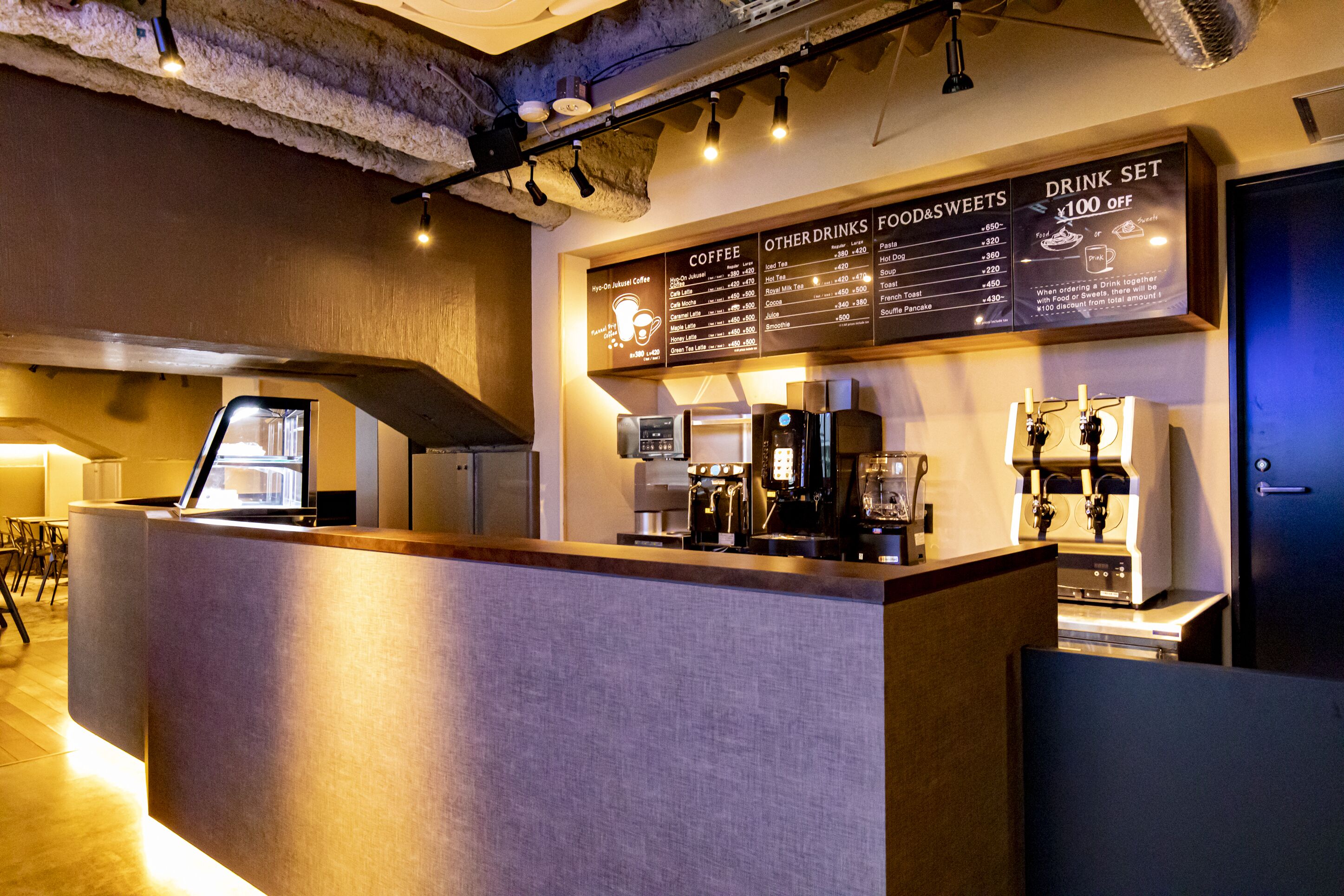 A coffee shop counter with a menu board displaying coffee and food options.