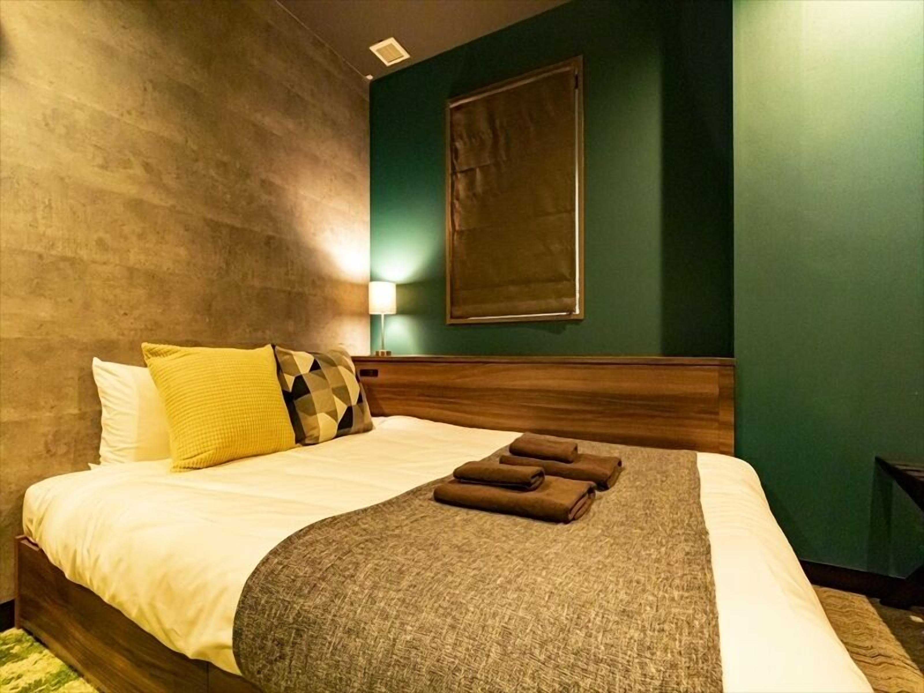 Een hotelkamer met een bed, een hoofdbord, een wandlamp en een schilderij.