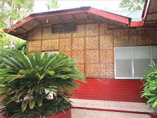 A building with a patterned exterior, a red roof, and a large potted plant in the foreground.